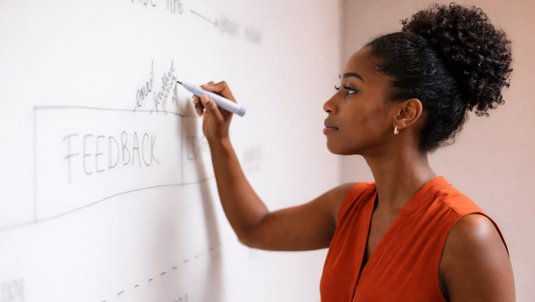 person writing feedback-related notes on whiteboard